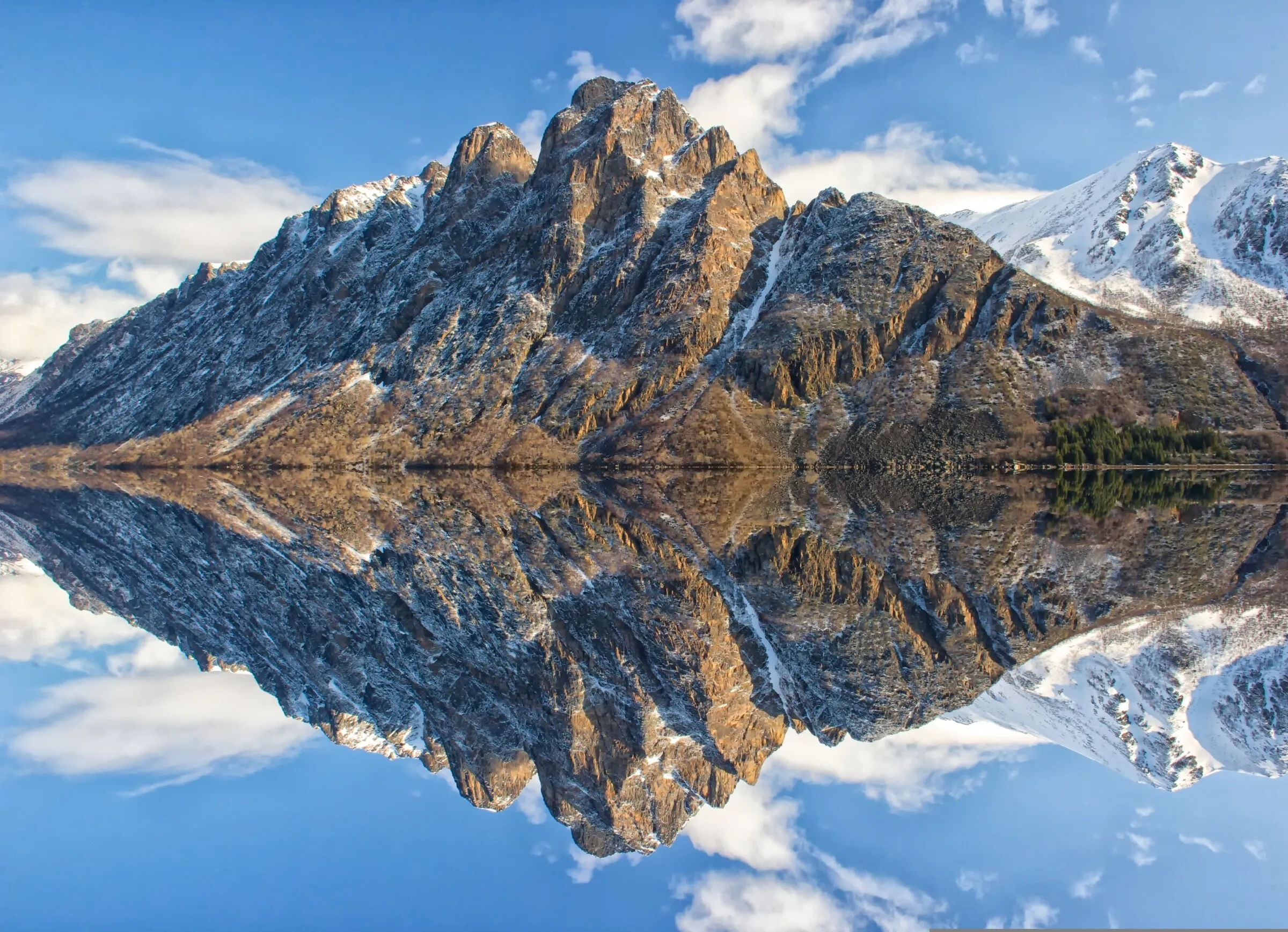 Snow-capped mountain peak reflected in a perfectly still lake
