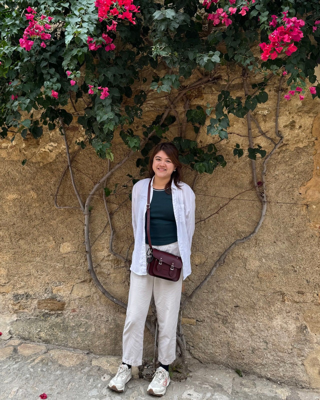 Sandra Huang standing among blooming bougainvillea on a sunlit street